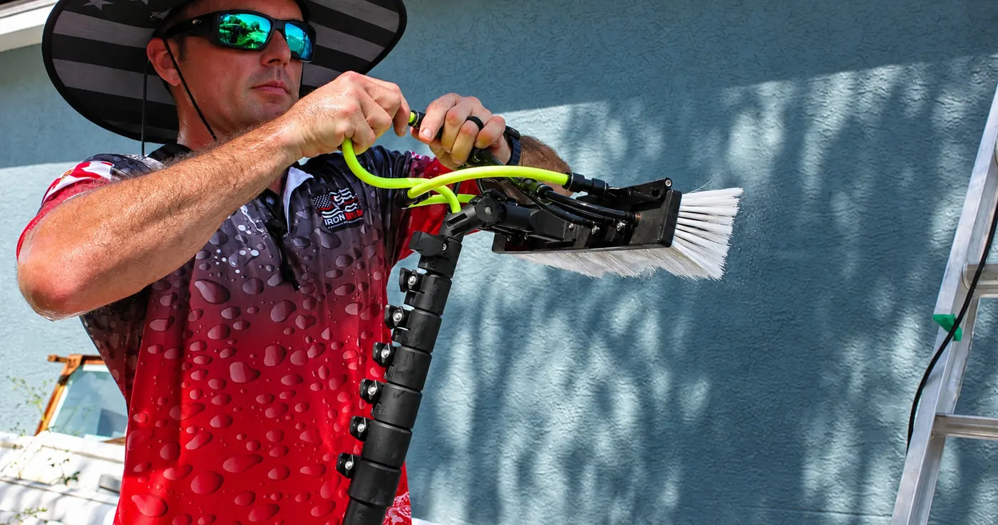 Close-up of an Iron Shield technician connecting the water line to a water-fed window brush head