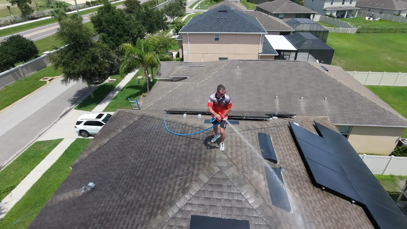 Iron Shield technician applying a controlled cleaning solution across an asphalt shingle roof
