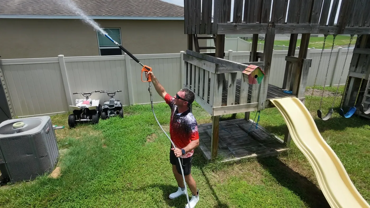 Iron Shield technician directing a controlled spray at the upper platform and roof of a wooden play structure