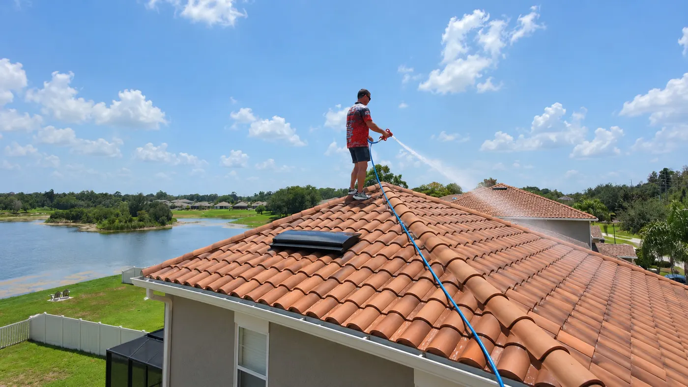 Iron Shield technician rinsing dirt and organic buildup from the surface of a terracotta tile roof