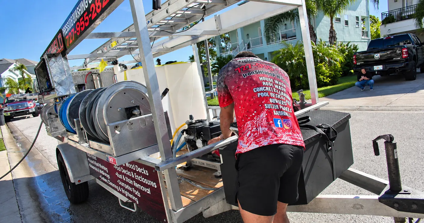 Iron Shield technician preparing the hose reels and equipment rack on the trailer ahead of a gas station cleaning