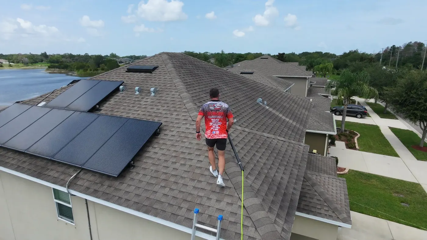 Iron Shield technician clearing algae streaks from the roof around a home solar panels