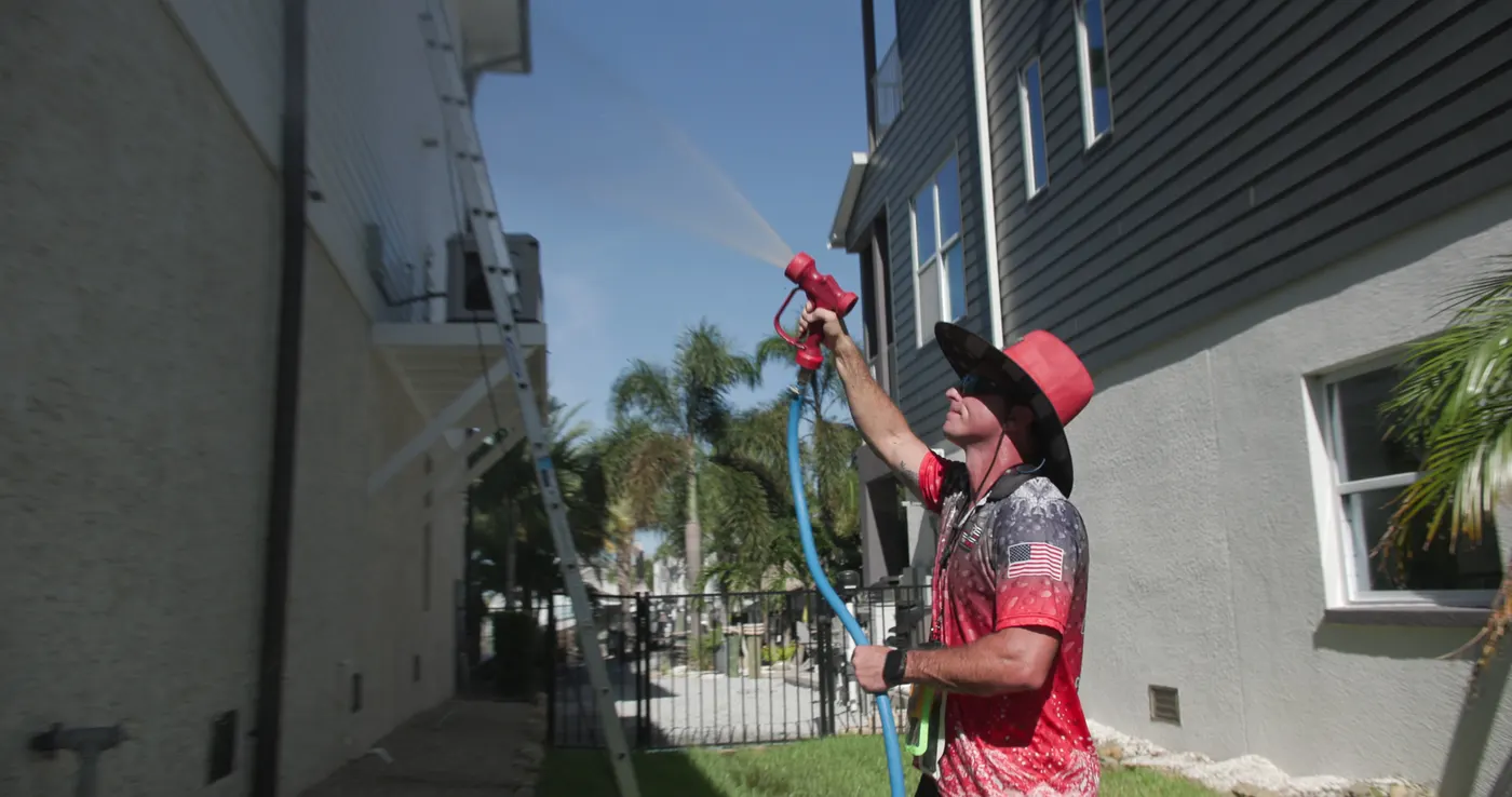 Iron Shield technician holding a controlled stream on the higher exterior surfaces of a home, out of reach from the ground